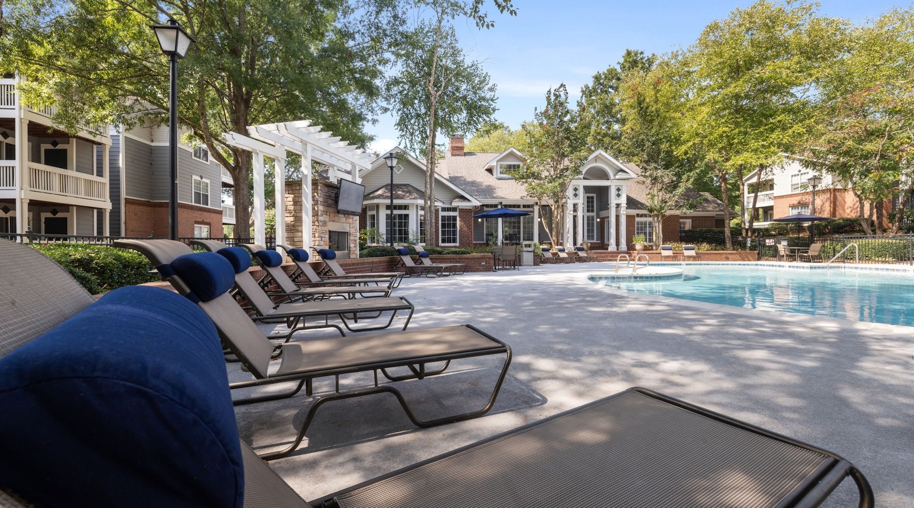 Relax and unwind poolside a pool with chairs and tables by it